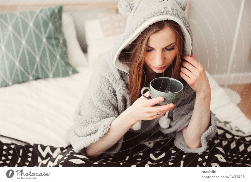 junge schöne Frau, die sich zu Hause auf dem Bett entspannt. Kaffee Tee Lifestyle Leben Erholung Schlafzimmer Erwachsene Kultur Wärme Mode sitzen träumen