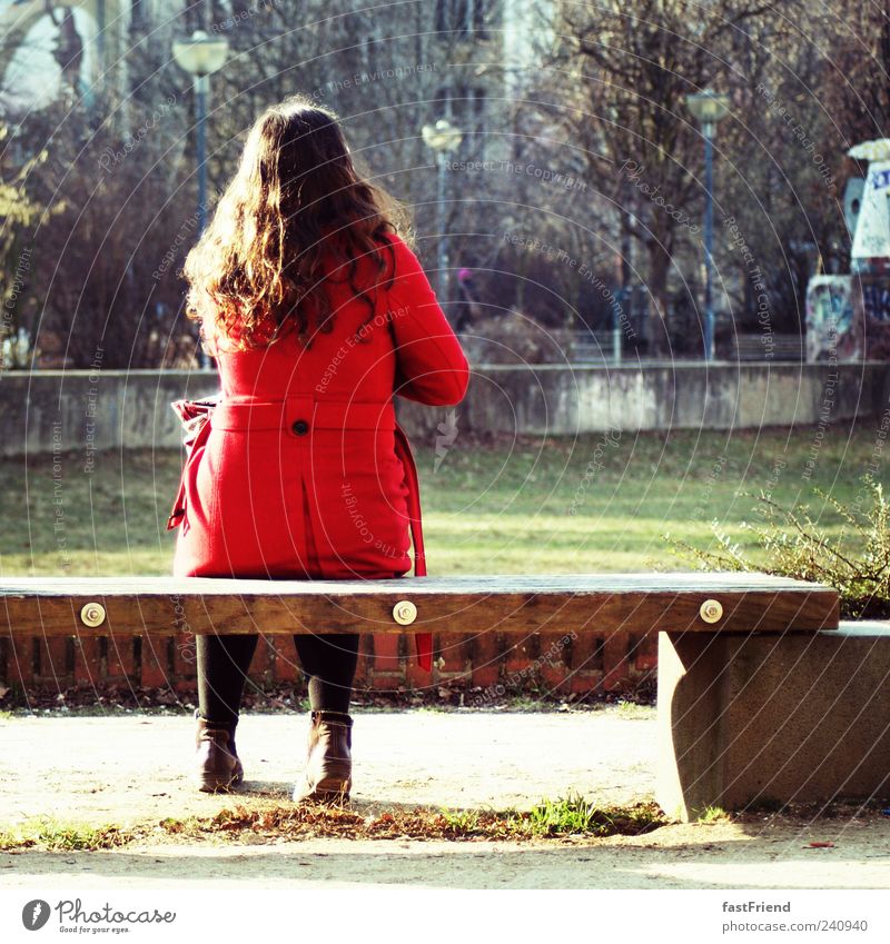 124 Sekunden Pause Frau Erwachsene Mensch Park Mantel schwarzhaarig Locken ruhig Einsamkeit Bank sitzen warten rot Holz Stein Farbfoto Außenaufnahme Tag