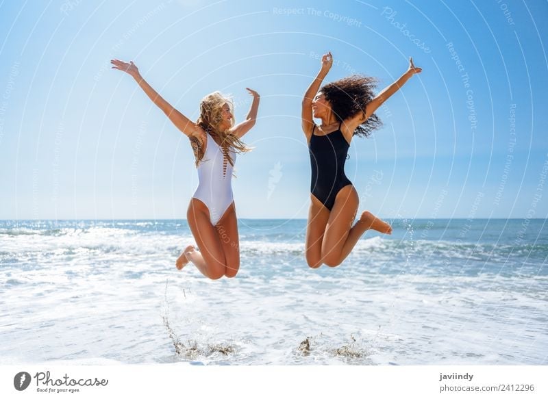 Zwei Frauen in Badebekleidung springen an einem tropischen Strand. Freude Ferien & Urlaub & Reisen Tourismus Sommer feminin Junge Frau Jugendliche Erwachsene