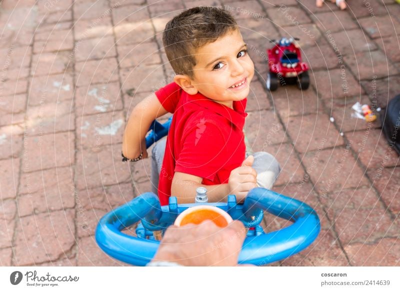 Die Hand des Vaters schiebt das Dreirad eines Kindes. Freude Spielen Sommer Garten Sport Junge Eltern Erwachsene Familie & Verwandtschaft Park Lächeln