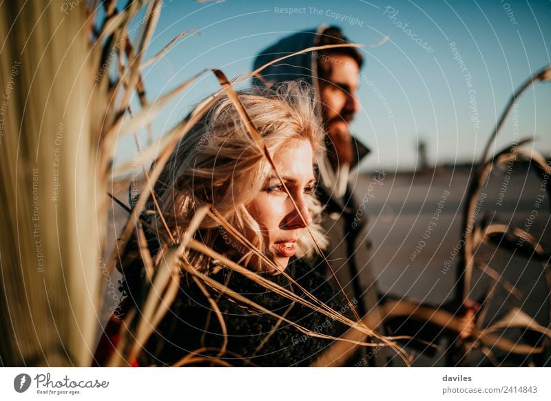 Blonde Frau und bärtiger Mann betrachten den Sonnenuntergang zwischen Pflanzenzweigen. Lifestyle Freude Glück schön Spielen Sommer Mensch Junge Frau Jugendliche