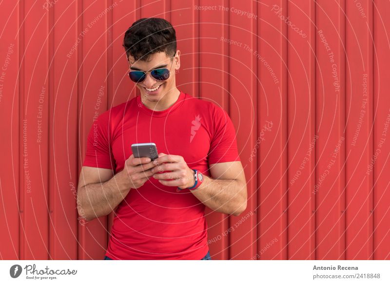 Mann auf Rot lesen Telefon Mensch Erwachsene Sonnenbrille brünett berühren Lächeln rot 20-25 Jahre alt 20s 30 Jahre alt attraktiv Tür Latein Lateinamerikaner
