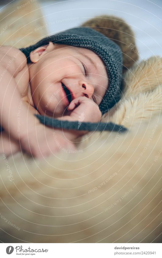 Neugeborenes Baby mit Pomponmütze schlafend und lachend auf Decke Glück schön Windstille Schlafzimmer Kind Mensch Frau Erwachsene Wärme Hut träumen authentisch