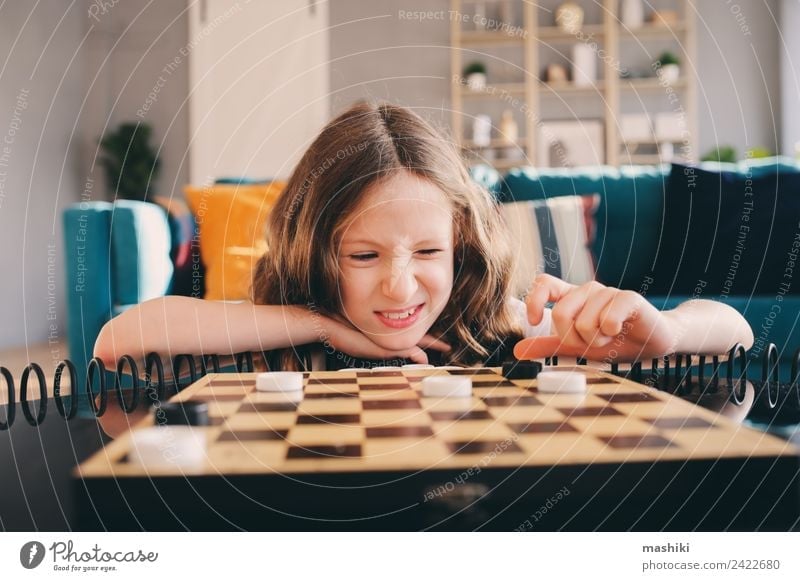 Lifestyle-Aufnahme von einem klugen Kind, das zu Hause Dame spielt. Freizeit & Hobby Spielen Schach Erfolg Mädchen Familie & Verwandtschaft Kindheit Spielzeug