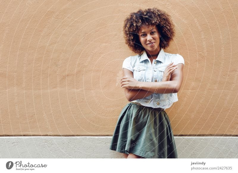 Junge schwarze Frau, Afro-Frisur, lächelnd in der Nähe einer Mauer auf der Straße Lifestyle Stil Glück schön Haare & Frisuren Gesicht Mensch Junge Frau
