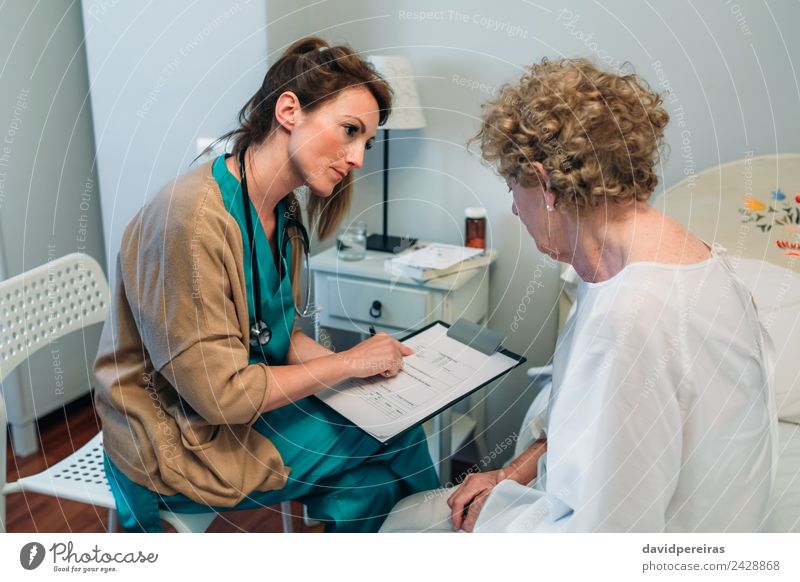 Ärztin füllt Fragebogen für eine ältere Patientin aus Gesundheitswesen Behandlung Krankheit Medikament Lampe Stuhl Arzt Krankenhaus Mensch Frau Erwachsene alt
