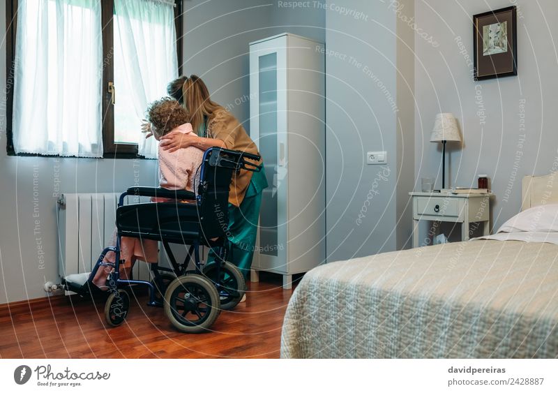 Betreuer mit einem älteren Patienten im Rollstuhl vor dem Fenster Lifestyle Gesundheitswesen Krankheit Medikament Arzt Krankenhaus Mensch Frau Erwachsene
