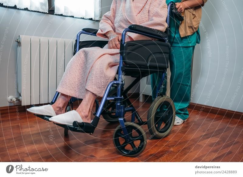 Arzt, der ältere Patienten im Rollstuhl trägt. Gesundheitswesen Krankheit Erholung Krankenhaus Mensch Frau Erwachsene Hausschuhe alt tragen authentisch