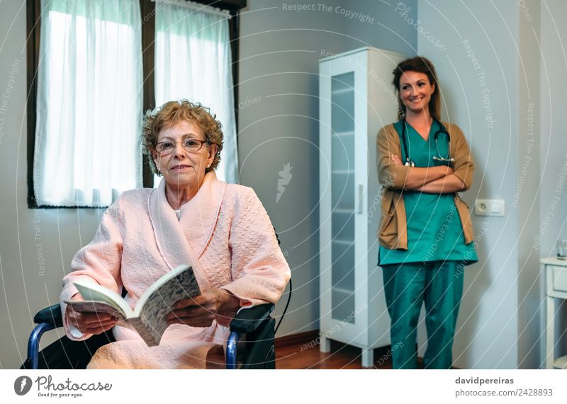 Älterer Patient posiert mit Arzt im Hintergrund Gesundheitswesen Krankheit Erholung lesen Schlafzimmer Krankenhaus Mensch Frau Erwachsene Buch alt Lächeln