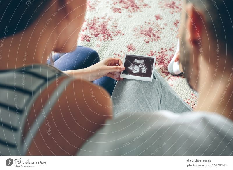 Paar schaut auf Ultraschall von ihrem Baby sitzen auf dem Bett Prüfung & Examen Mensch Frau Erwachsene Mann Eltern Mutter Vater Familie & Verwandtschaft Partner