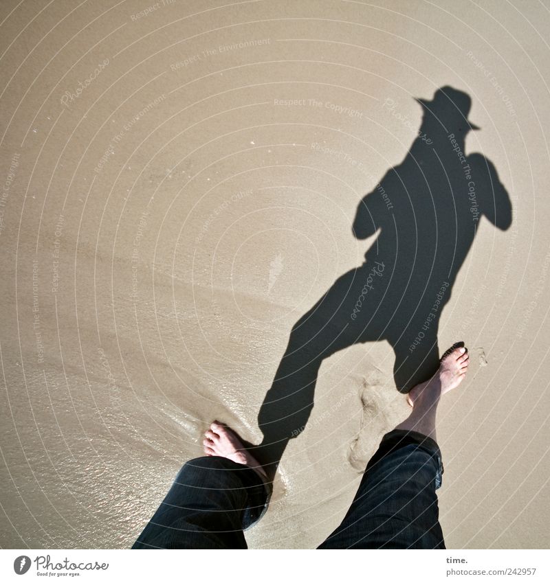 Schattenknipser Strand maskulin Mann Erwachsene Beine Fuß Sand Wasser Hose Hut nass Barfuß feucht Farbfoto Gedeckte Farben Außenaufnahme Textfreiraum links