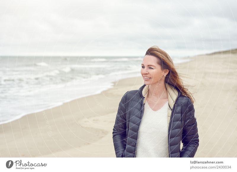 Frau, die an einem bewölkten Tag am Strand spazieren geht. Freizeit & Hobby Freiheit Meer Erwachsene 1 Mensch 45-60 Jahre Sand Wolken Herbst Küste Nordsee