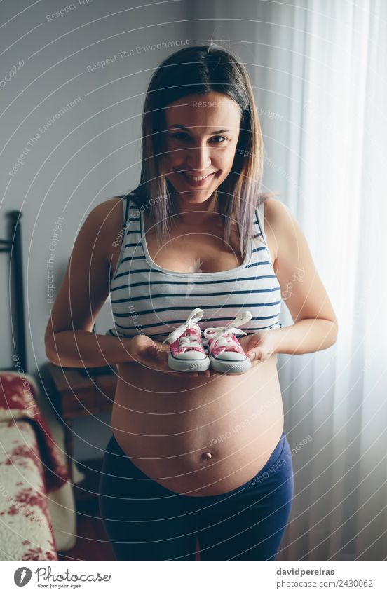 Schwangerschaft zeigt Babysneakers Lifestyle Glück schön Leben Fotokamera Mensch Frau Erwachsene Mutter Schuhe Turnschuh Lächeln warten authentisch Fröhlichkeit