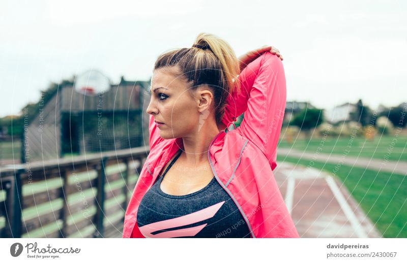Junge Frau, die die Arme streckt, bevor sie im Freien trainiert. Lifestyle Sport Joggen Rennbahn Mensch Erwachsene Park Straße blond Zopf Linie Fitness