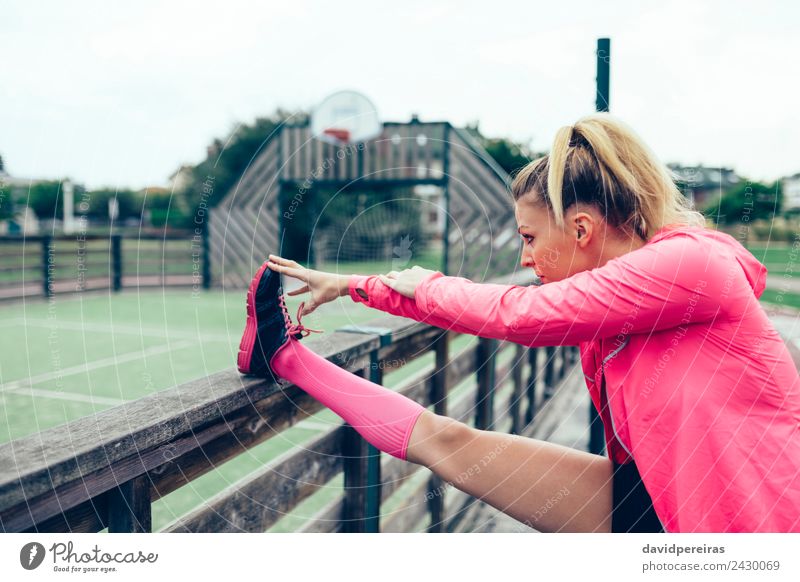 Junge Frau, die vor dem Training im Freien die Beine streckt. Lifestyle Sport Joggen Rennbahn Mensch Erwachsene Arme Park Straße Turnschuh blond Zopf Linie
