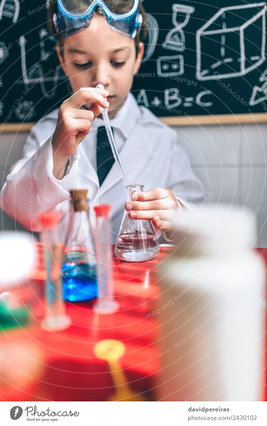 Ernsthaftes Kind beim Spielen mit chemischen Flüssigkeiten Flasche Glück Wohnung Tisch Wissenschaften Klassenraum Tafel Labor Mensch Junge Kindheit Hand