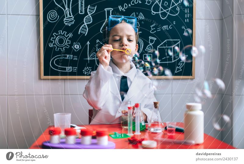 Junge spielt mit Seifenblasen gegen eine gezeichnete Wandtafel Flasche Freude Glück Spielen Wohnung Tisch Wissenschaften Kind Schule Klassenraum Tafel Labor