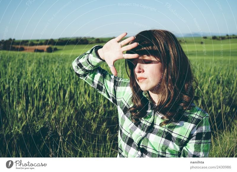 Junge Frau bedeckt ihr Gesicht vor der Sonne auf einem grünen Feld. Lifestyle Stil Gesundheit Wellness Sinnesorgane Erholung Sommer Landwirtschaft