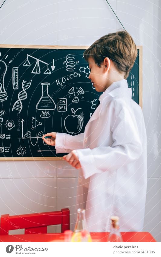 Kind mit Zeichnungen auf der Tafel mit Marker Glück Spielen Wohnung Wissenschaften Klassenraum Labor sprechen Mensch Junge Kindheit authentisch klein Neugier