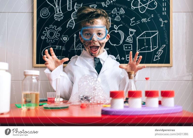 Glücklicher kleiner Junge spielt aufgeregt mit experimentellen Ergebnissen. Gesicht Spielen Wohnung Tisch Wissenschaften Kind Schule Klassenraum Tafel Labor