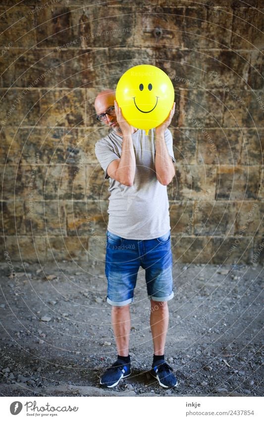 Drittes Bild mit gelbem Smiley Lifestyle Freude Freizeit & Hobby Spielen Mann Erwachsene 1 Mensch 30-45 Jahre 45-60 Jahre Luftballon Zeichen festhalten Lächeln