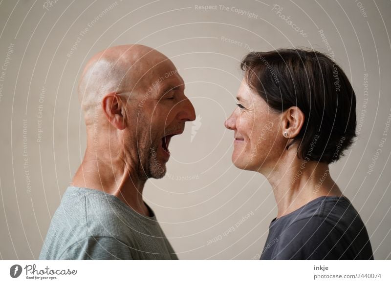 Mann und Frau stehen sich gegenüber. Der Mann öffnet weit den Mund, die Frau grinst. Lifestyle Freizeit & Hobby Erwachsene Freundschaft Paar Partner Leben
