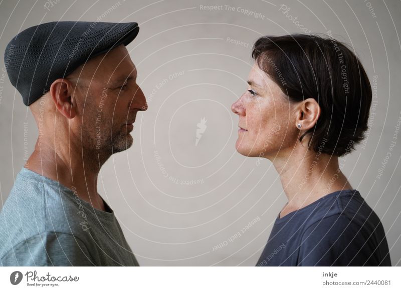 Mann und Frau stehen sich gegenüber Zusammensein Zusammenhalt Erwachsene Blick Blick in die Kamera Angesicht zu Angesicht Vor hellem Hintergrund Profil Porträt