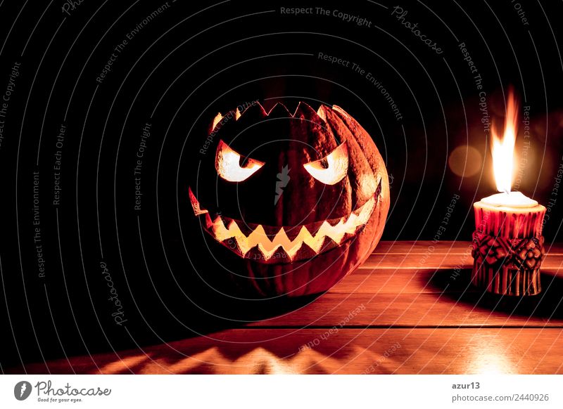 Gruseliger geschnitzter Halloween Kürbis neben brennender Kerze Kopf Auge Mund Kunst Natur Herbst glänzend Lächeln lachen leuchten Aggression alt bedrohlich
