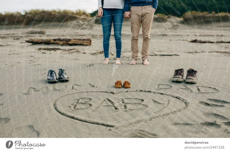 Mama, Papa und Baby auf den Sand geschrieben, mit den Eltern dahinter. Lifestyle Strand Winter Mensch Frau Erwachsene Mann Mutter Vater Familie & Verwandtschaft