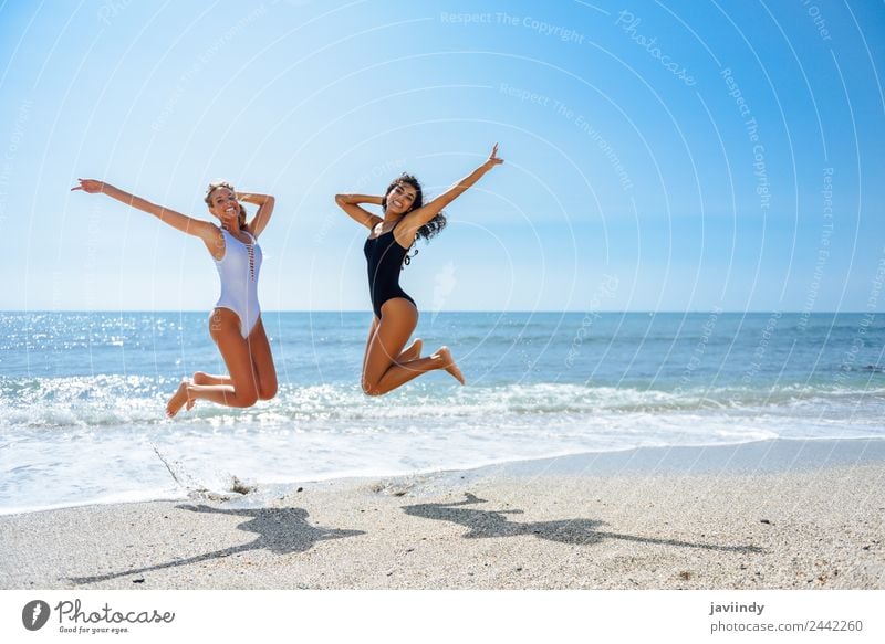 Zwei glückliche Mädchen, die an einem tropischen Strand springen. Freude Ferien & Urlaub & Reisen Tourismus Sommer Meer Mensch feminin Junge Frau Jugendliche