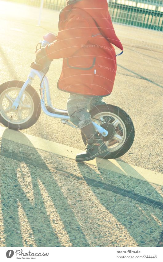 der sonne entgegen laufrad Kind Kinderfahrrad Gegenlicht stoßen Geschwindigkeit fahren abfahrt Spielen Zwerg rot Schatten fahrradfahren lernen üben Bewegung