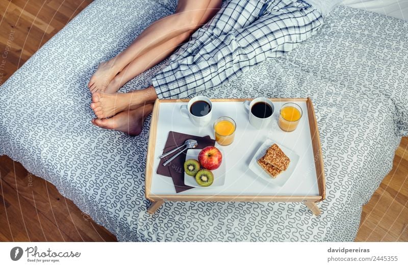 Gesundes Frühstück auf Tablett und Paar Beine über dem Bett Frucht Apfel Saft Kaffee Lifestyle Glück Erholung Freizeit & Hobby Schlafzimmer Frau Erwachsene Mann