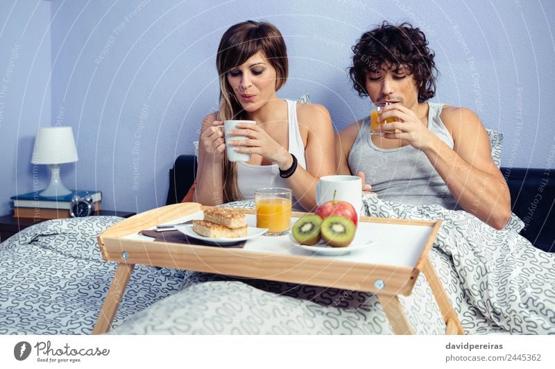 Paar beim Frühstück im Bett, serviert auf dem Tablett. Frucht Apfel Saft Kaffee Lifestyle Glück schön Erholung Freizeit & Hobby Schlafzimmer Frau Erwachsene