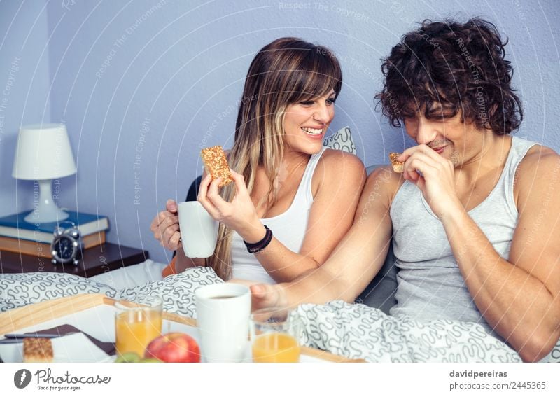 Ein Paar lacht und frühstückt zu Hause im Bett. Frucht Apfel Frühstück Saft Kaffee Lifestyle Glück schön Erholung Freizeit & Hobby Schlafzimmer Frau Erwachsene