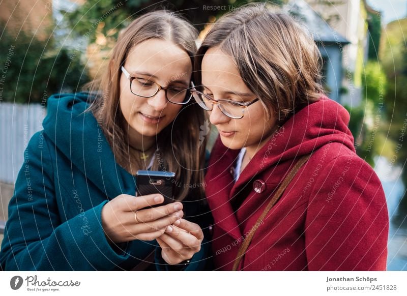 Zwillingsschwestern schauen gemeinsam auf ein Smartphone Lifestyle Stil Freude Glück Mensch feminin Junge Frau Jugendliche Geschwister Schwester 2 Fröhlichkeit