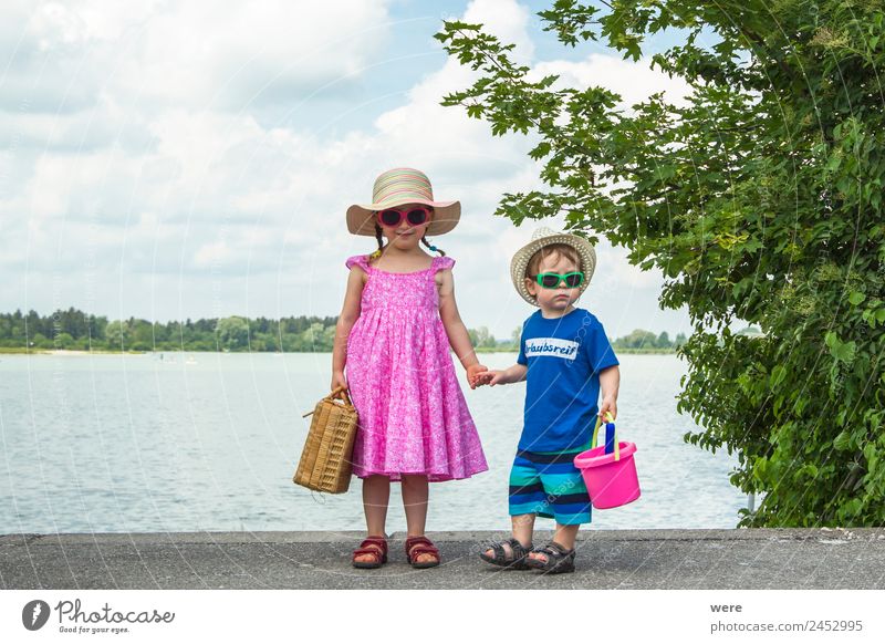 A boy and a girl in toddlerhood are standing on a log in summer clothes, looking to the left Strand Mensch Baby Familie & Verwandtschaft Erholung