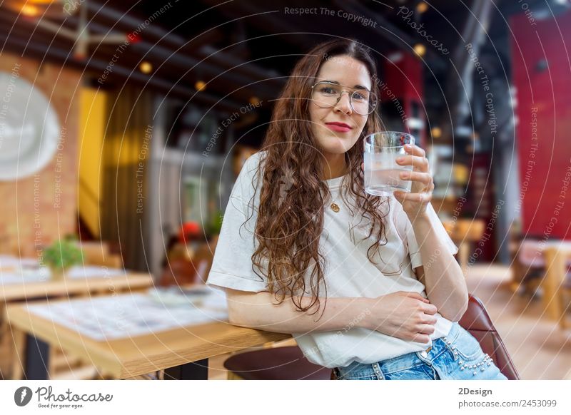 Hübsche junge Frau hält ein Glas Wasser. Frühstück Getränk trinken Kaffee Lifestyle Glück schön Gesundheitswesen Erholung Sommer Stuhl Tisch Restaurant Mensch