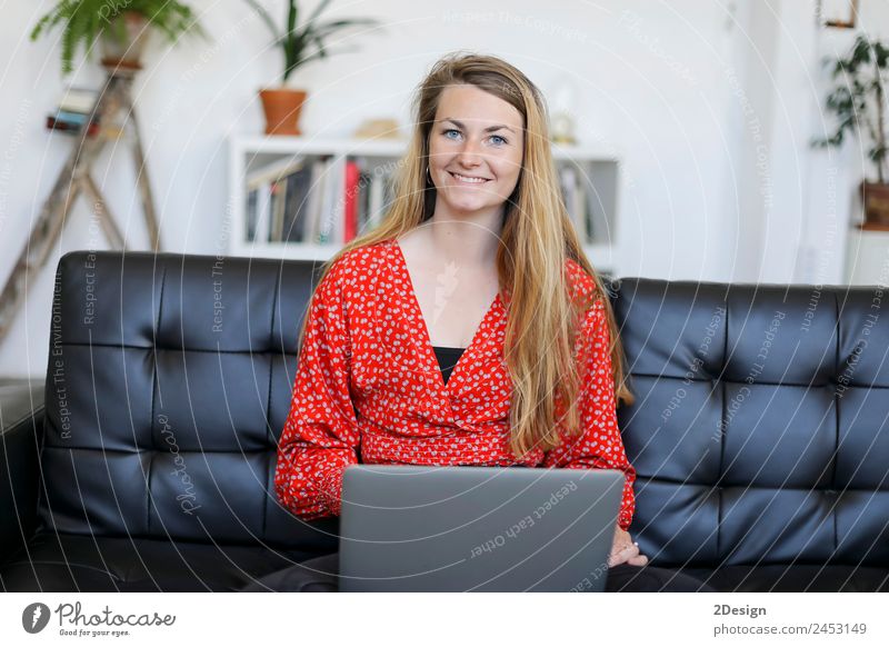 Unternehmerin in rotem Hemd arbeitet mit einem Laptop und sitzt zu Hause auf einer Couch kaufen Glück schön Sofa Schule lernen Studium Arbeit & Erwerbstätigkeit