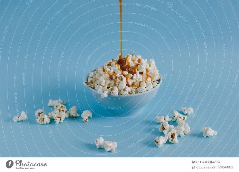 Schüssel mit Popcorn und Karamellsauce auf blauem Hintergrund Getreide Süßwaren Ernährung Essen Schalen & Schüsseln Freizeit & Hobby Tisch Party Veranstaltung