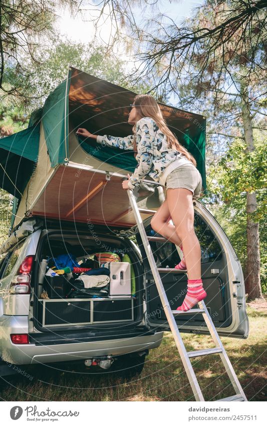 Frau steht in einer Leiter und öffnet das Zelt über dem Auto. Lifestyle Freude Glück Erholung Freizeit & Hobby Ferien & Urlaub & Reisen Ausflug Abenteuer