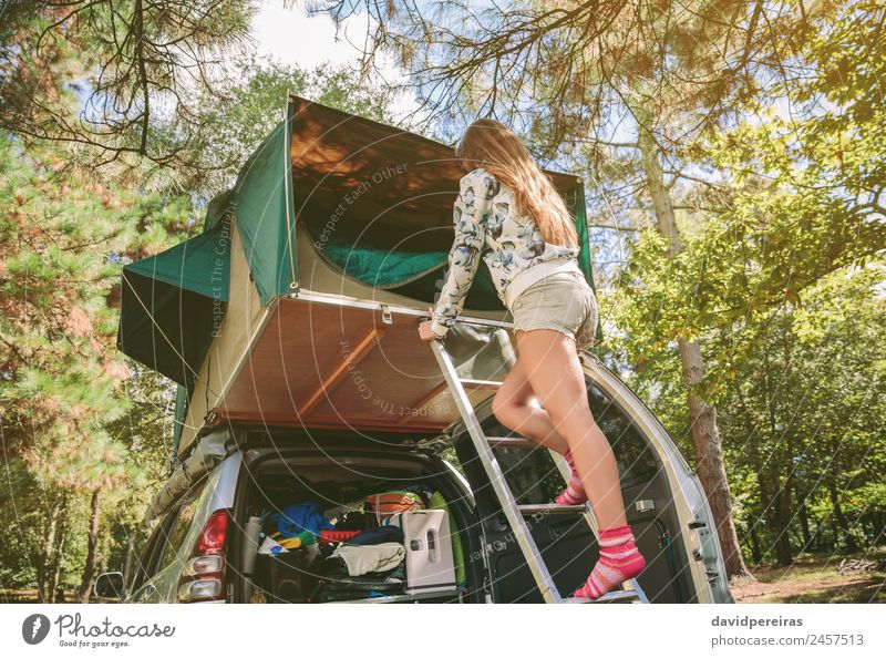 Frau steht in einer Leiter und öffnet das Zelt über dem Auto. Lifestyle Freude Glück Erholung Freizeit & Hobby Ferien & Urlaub & Reisen Ausflug Abenteuer