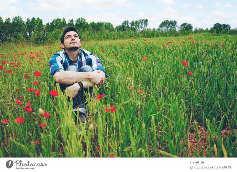 Junger Mann allein auf einem Feld mit grünem Weizen. Lifestyle Stil Gesundheit Wellness harmonisch Wohlgefühl Sinnesorgane Erholung Abenteuer Ferne Freiheit