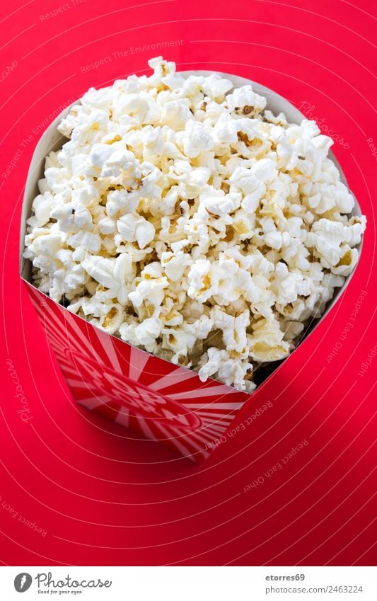 Gestreifte Box mit Popcorn auf rotem Hintergrund. Lebensmittel Ernährung Essen Bioprodukte Fingerfood Popkorn Kino Salz Butter Snack weiß lecker Mais Streifen