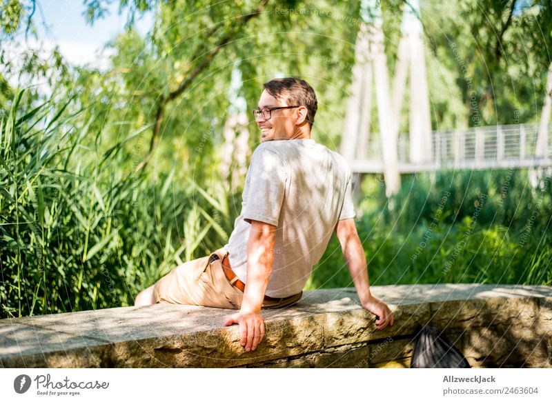 Portrait von einem jungen Mann in der Natur Porträt Junger Mann 1 Mensch Brille grün Tag sitzen Erholung Pause ausruhend genießen Park Ferien & Urlaub & Reisen