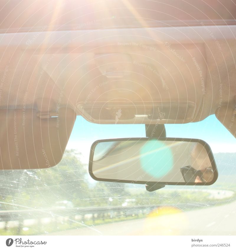 Sonnige Autofahrt. Blick durch die Windschutzscheibe auf die Autobahn. Augen und Brille der Fahrerin als Spiegelung im Rückspiegel Ferien & Urlaub & Reisen