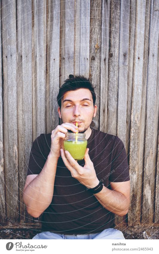 Junger Mann trinkt Gemüsesaft Bioprodukte Vegetarische Ernährung Getränk trinken Erfrischungsgetränk Saft Milchshake Glas Trinkhalm Lifestyle Stil