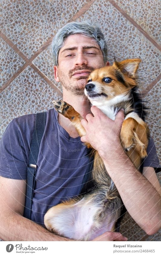 Porträt eines Mannes mit seinem Hund auf dem Boden liegend. Tier Haustier Backstein berühren genießen Liebe Zusammensein modern natürlich positiv blau braun