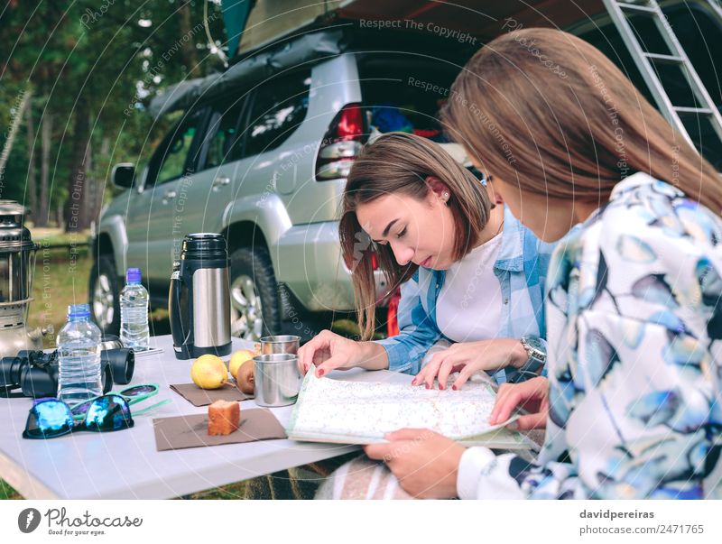 Junge Frauen, die eine Roadmap mit 4x4 im Hintergrund suchen. Frühstück Kaffee Lifestyle Freude Erholung Freizeit & Hobby Ferien & Urlaub & Reisen Ausflug