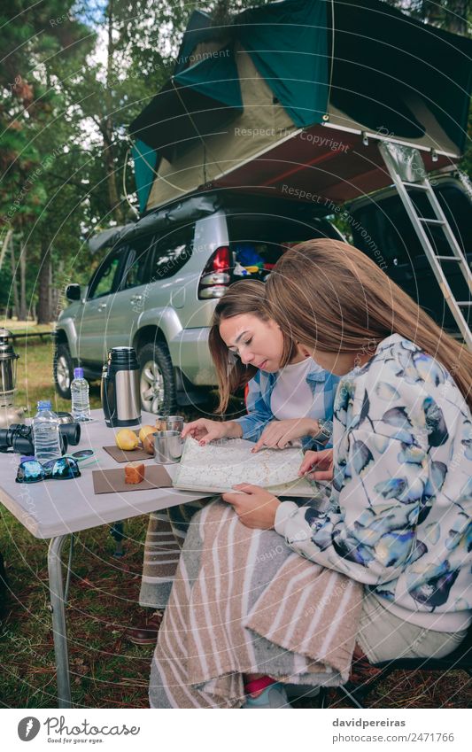 Junge Frauen auf der Suche nach einer Roadmap mit Fahrzeug im Hintergrund Frühstück Kaffee Lifestyle Freude Erholung Freizeit & Hobby Ferien & Urlaub & Reisen