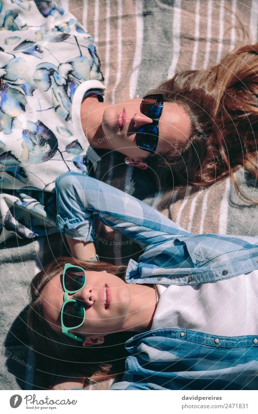 Zwei Frauen mit Sonnenbrille, die liegen und ein Sonnenbad nehmen. Lifestyle Freude Glück schön Erholung Freizeit & Hobby Sommer Fotokamera Mensch Erwachsene